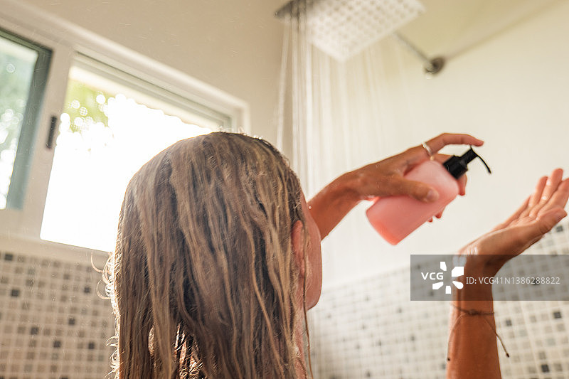 女人淋浴并使用粉色护发素图片素材