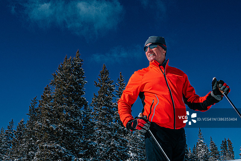 一位快乐的越野滑雪者站在科罗拉多州大梅萨国家森林的雪道上，手持滑雪杖的低角度特写肖像图片素材