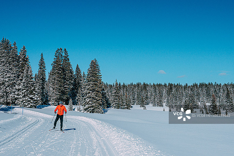 在科罗拉多州阳光明媚的一天，越野滑冰者沿着一条平整的小路以V2队形滑雪的广角照片图片素材