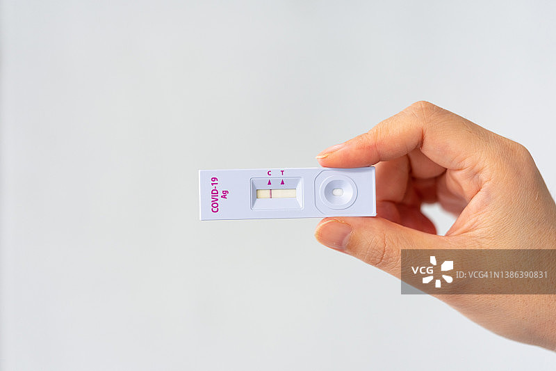 手持新冠病毒阴性检测结果，显示SARS CoV-2快速抗原检测试剂盒（ATK），冠状病毒感染防护概念图片素材