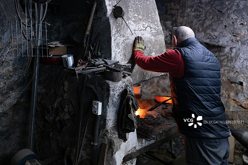 工作服铁匠在熔炉内加工熔融金属图片素材