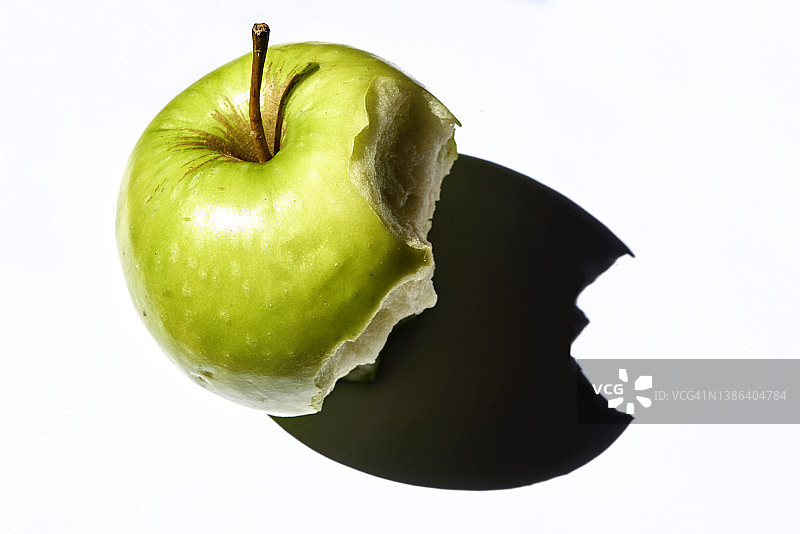 被咬过的青苹果：白色背景上的特写镜头图片素材