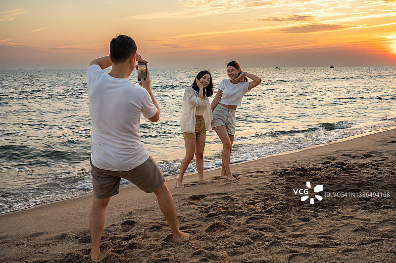 在海滩上拍照的快乐年轻人图片素材