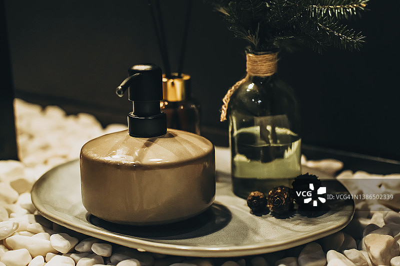 托盘上的皂液器、香薰棒和冷杉树枝罐图片素材