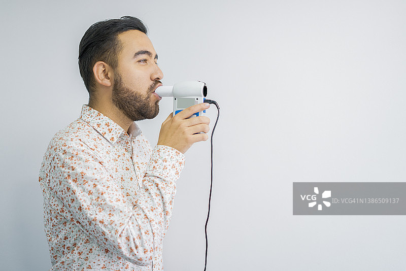 拉丁裔患者通过吹入医疗设备进行呼吸测试，以测量肺活量图片素材