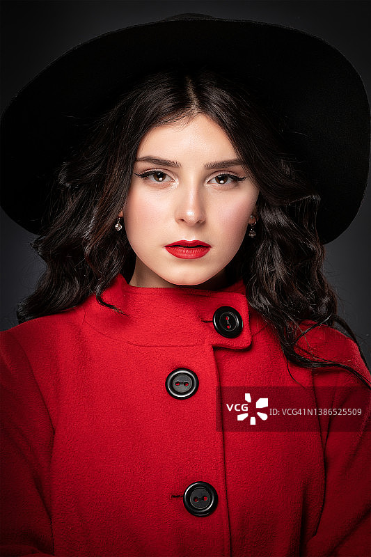 一位身材苗条的棕发女子，长卷发，妆容精致，身穿红色外套图片素材