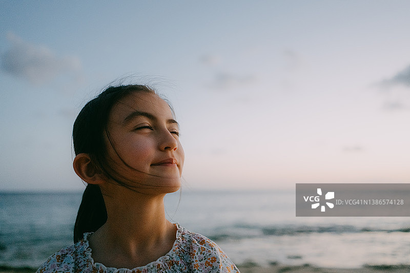 在日落时分海滩上放松的可爱年轻女孩图片素材