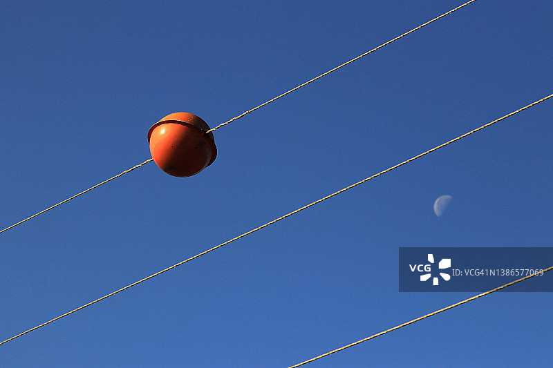 蓝色天空下电力线上的红色警示球图片素材
