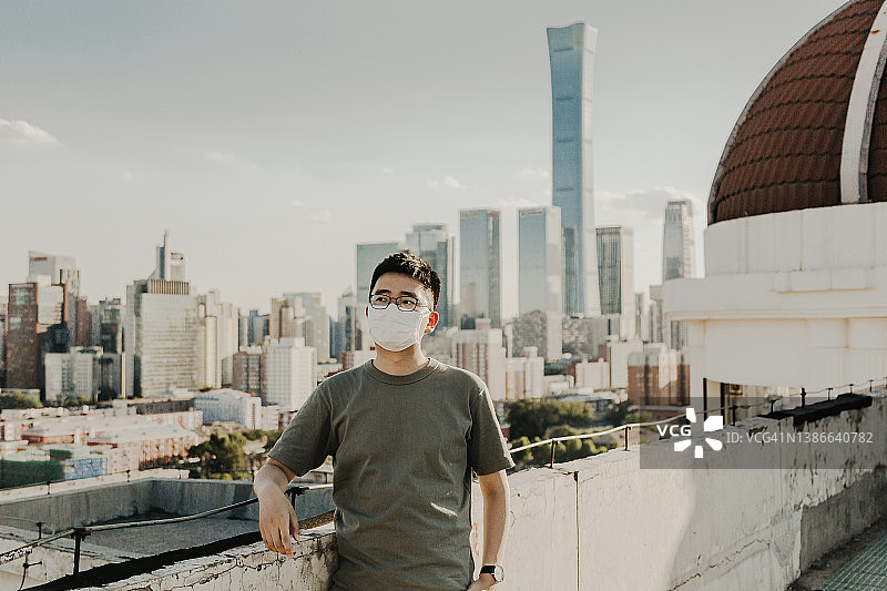 戴口罩的亚洲男人站在北京中央商务区图片素材