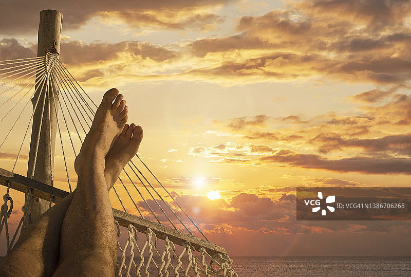 日落时吊床上的男脚图片素材