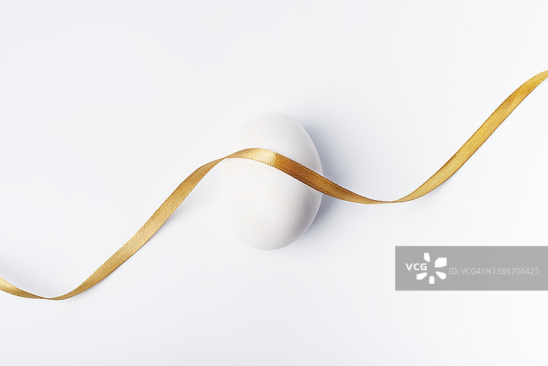白色背景上系着金色丝带的白色鸡蛋图片素材