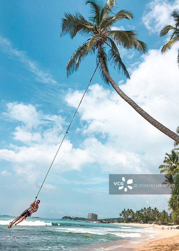 男子在斯里兰卡达拉维拉海滩荡秋千图片素材