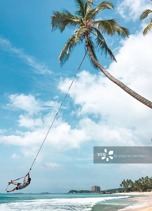 男子在斯里兰卡达拉维拉海滩荡秋千图片素材
