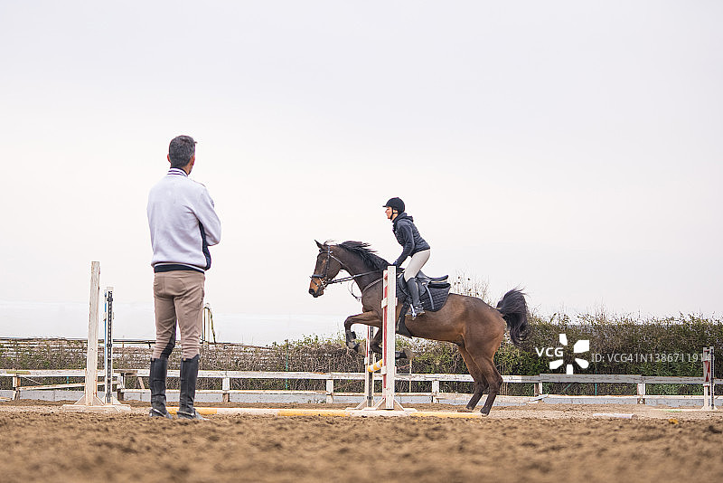 年轻女人在教练的指导下学习跨越障碍图片素材