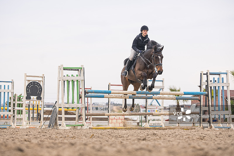 年轻女骑手在表演中跳过障碍图片素材