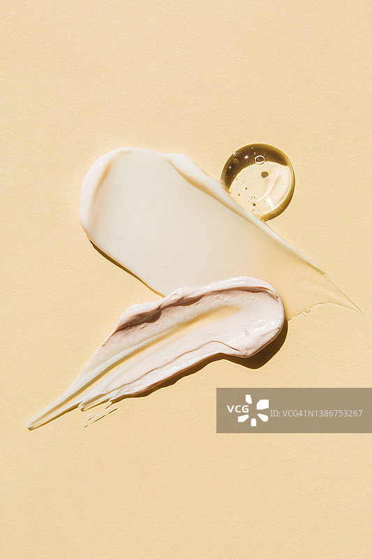 米色背景上的彩色化妆品涂抹纹理，面霜、面膜、凝胶、精华液样品俯视图图片素材