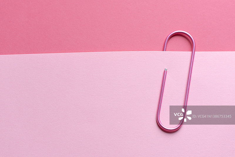 一个大的粉红色回形针夹着一张粉红色的纸图片素材