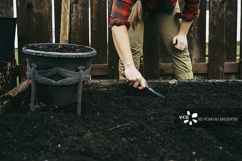 用手动叉子在种植箱的泥土中挖沟的女人特写图片素材