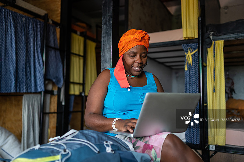 在宿舍卧室里用笔记本电脑工作的非洲裔女人图片素材