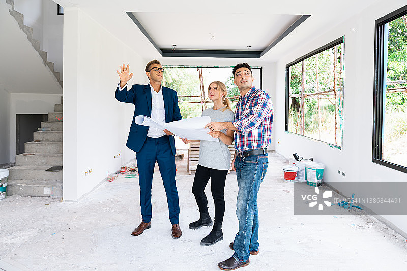 西装男人与一对夫妇在未完工的建筑里交谈图片素材