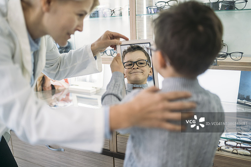 照镜子看新眼镜的男孩图片素材