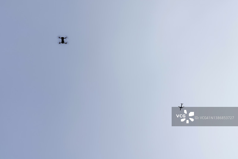 无人机与飞机在蔚蓝天空下的景象图片素材