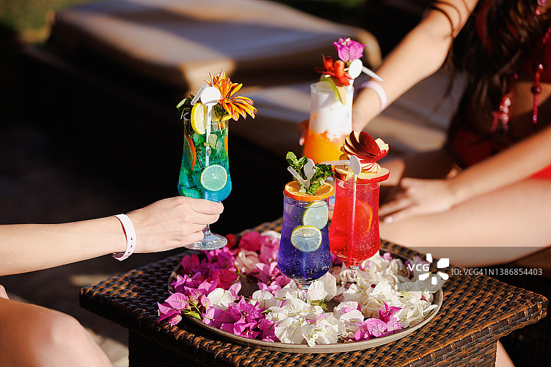 从摆满花瓣的托盘中取各种鸡尾酒图片素材