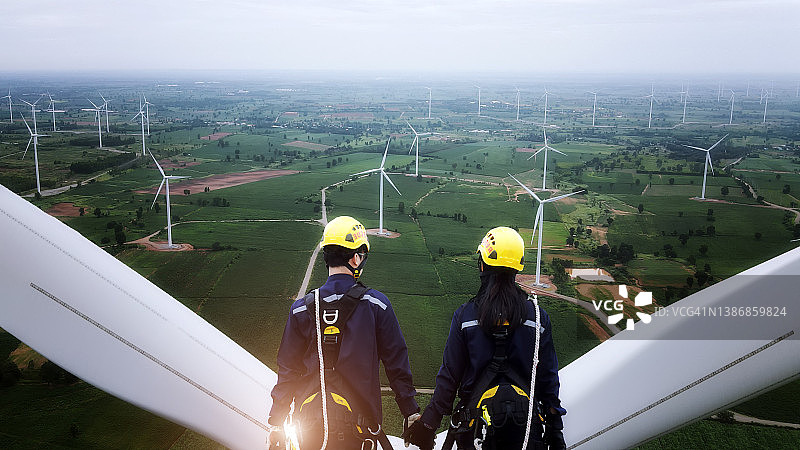 两名电力工程师身穿个人防护设备在风力涡轮机顶部工作图片素材
