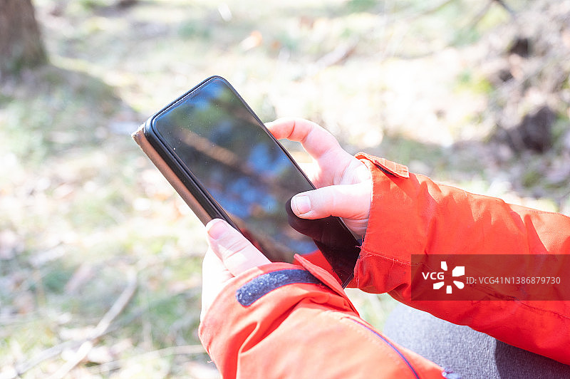 年轻人在森林里用智能手机网购图片素材