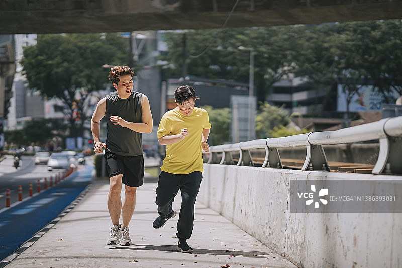 中国籍唐氏综合征青年男子与父亲一起跑步，享受户外活动图片素材