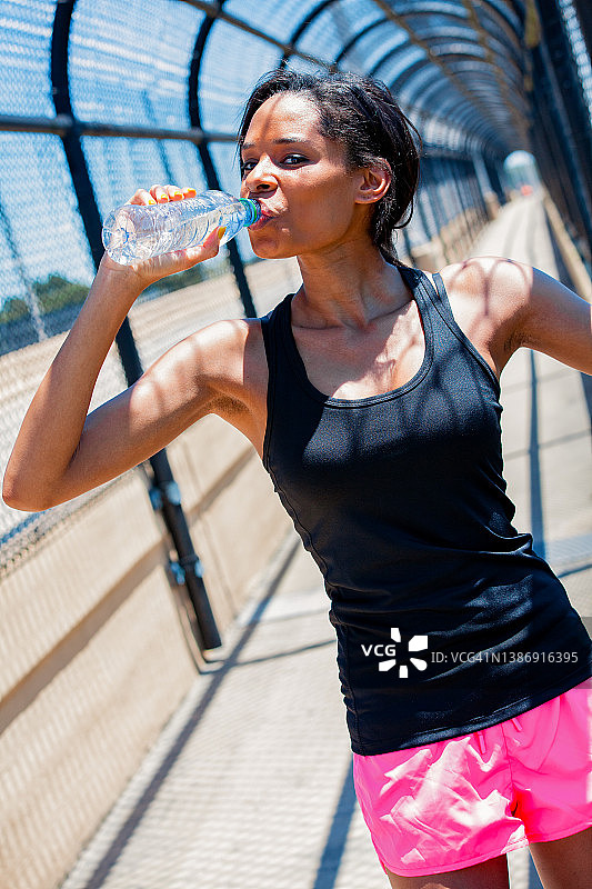 非裔美国女人在锻炼时喝瓶装水图片素材
