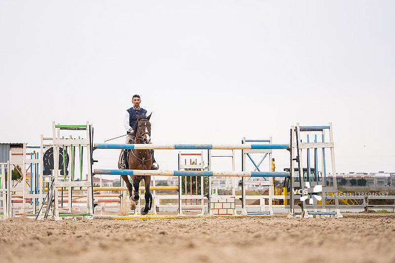 场地障碍赛：骑手和马跃过障碍图片素材