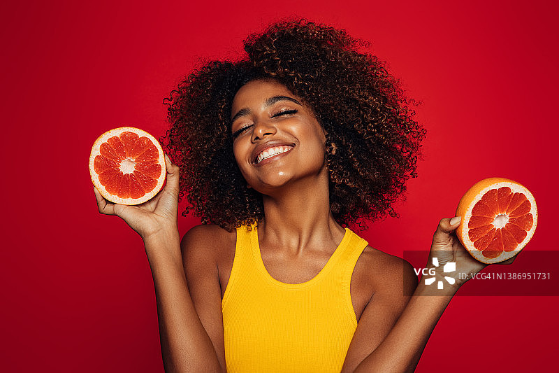 拿着葡萄柚的漂亮非洲女人图片素材