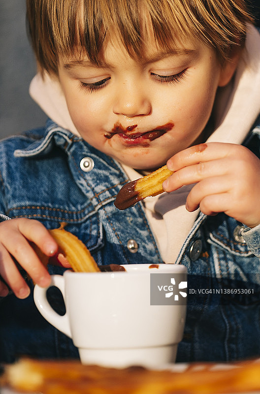 脸上有巧克力的小男孩在吃糕点图片素材