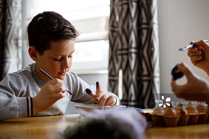 孙子和奶奶坐在桌旁，为复活节彩蛋涂色图片素材