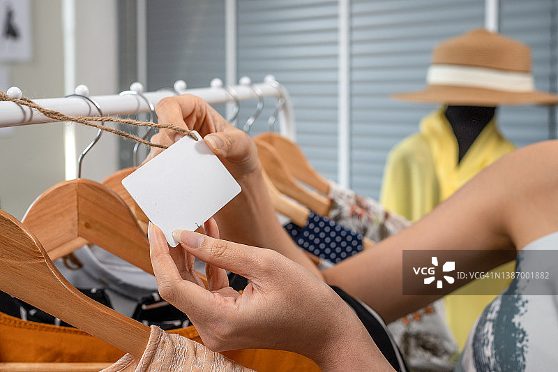 近距离拍摄：时装店木制衣架上的空白价格标签和T恤图片素材