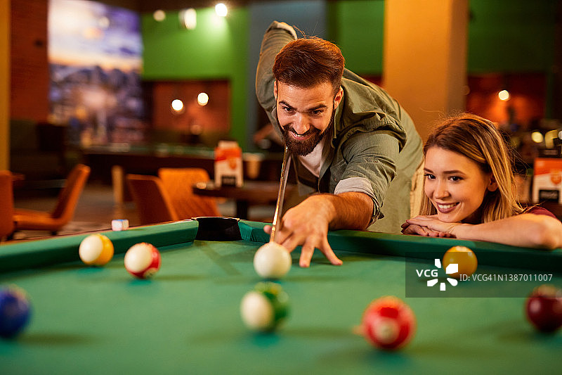 快乐的年轻情侣在台球厅约会打台球图片素材
