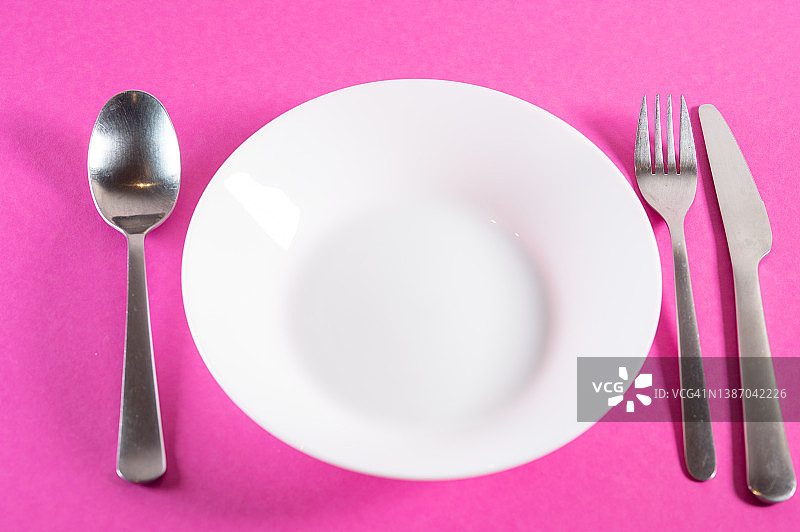 粉色桌面上带刀叉的空餐盘图片素材