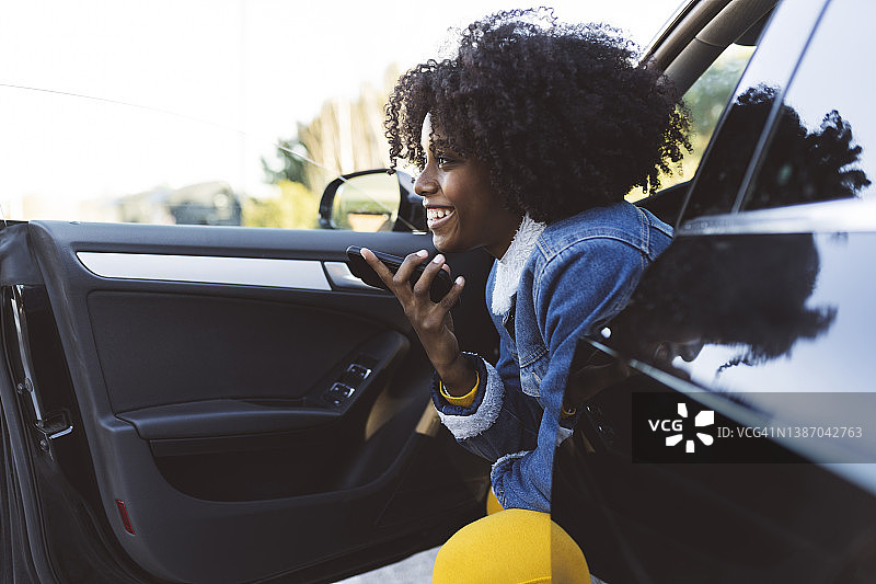 坐在车里用扬声器讲手机的快乐女人图片素材