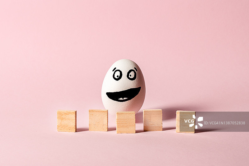 画有微笑字母的鸡蛋，幸福快乐的概念，粉色背景图片素材