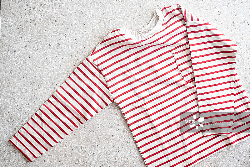 混凝土背景上红白条纹长袖T恤的特写，顶视图图片素材