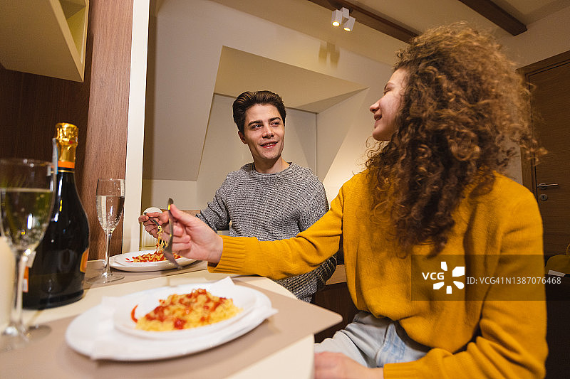 年轻情侣在家浪漫晚餐，品尝香槟和意大利面图片素材