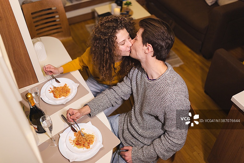 年轻情侣在家浪漫晚餐，品尝香槟和意大利面图片素材