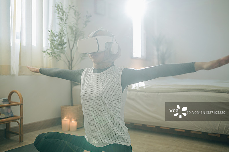 年轻穆斯林妇女在家使用VR头显锻炼图片素材