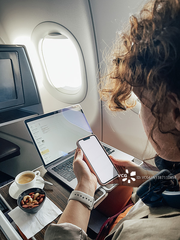 坐在飞机上使用智能手机的白人女性图片素材