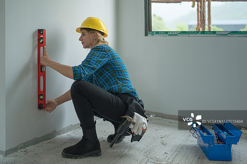 在墙上使用水平仪的女建筑工人图片素材