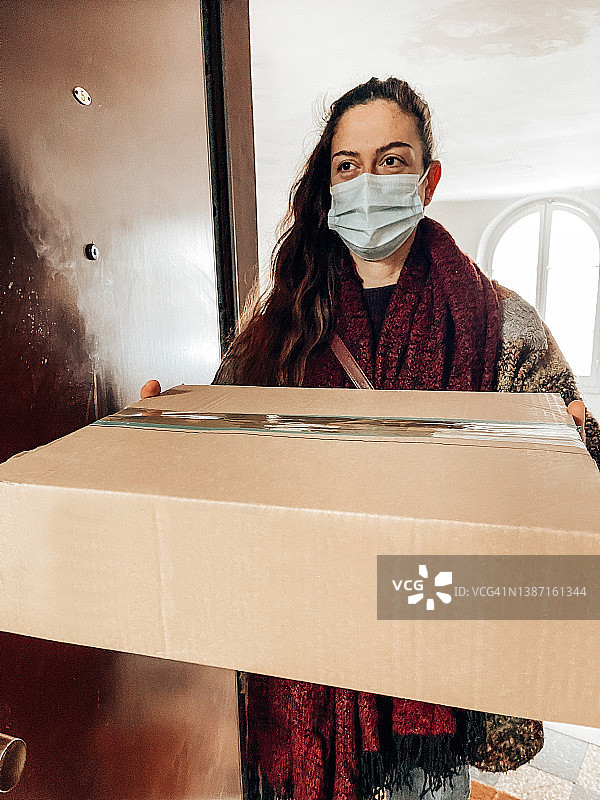 戴着口罩拿着盒子的女人图片素材