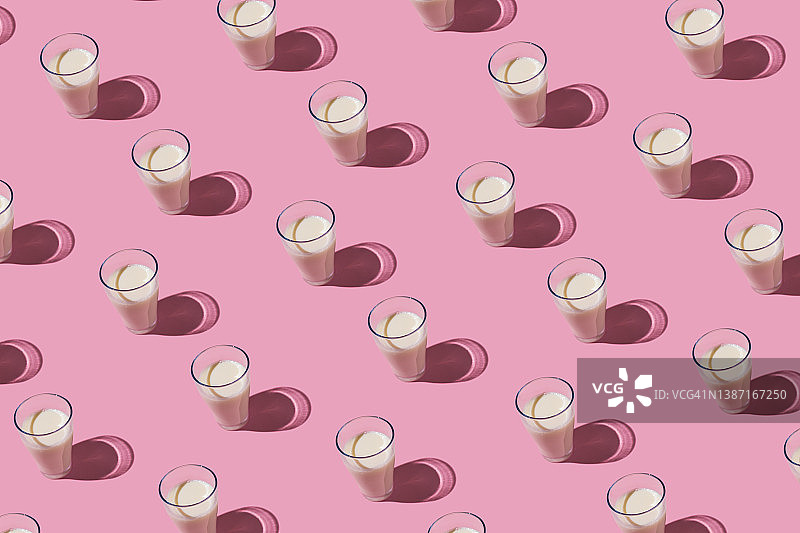 粉色背景下装满牛奶的玻璃杯图案，乳制品概念图片素材