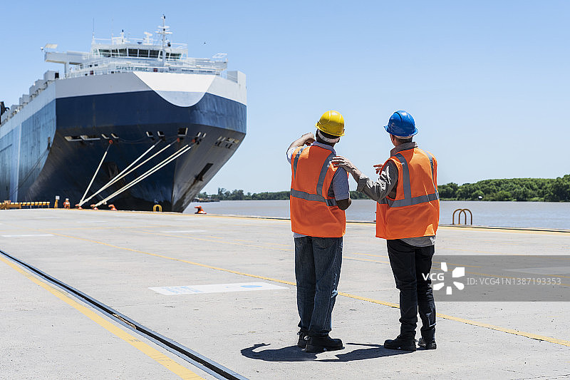 码头控制人员讨论并查看船只图片素材