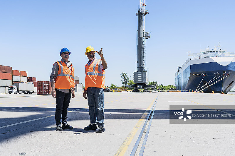 男工头工程师和码头工人讨论工作，同时在货运场站着并指点图片素材